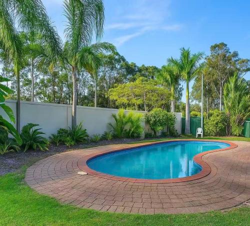a swimming pool in a yard with a brick driveway at Harbour Town Cozy Suite in Gold Coast