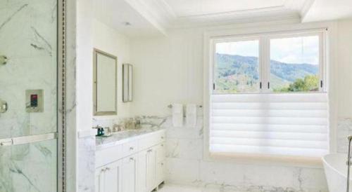 ein weißes Bad mit einer Dusche und einem Fenster in der Unterkunft Hotel Jerome, An Auberge Resort in Aspen