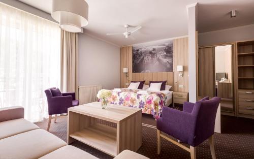 a hotel room with a bed and purple chairs at Willa Spa Scaliano in Kudowa-Zdrój