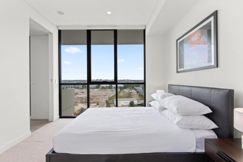 a bedroom with a bed and a large window at Luxe 2-Bed: Modern Interiors Balcony & BBQ Area in Sydney