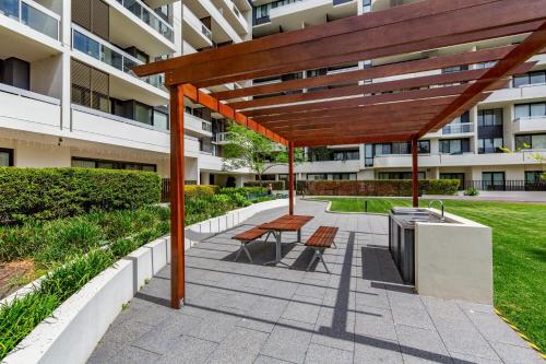 a bench under a wooden pergola in front of a building at Luxe 2-Bed: Modern Interiors Balcony & BBQ Area in Sydney