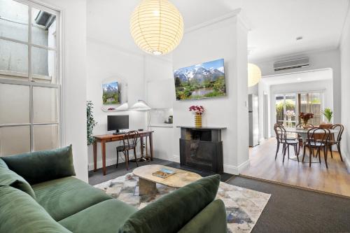 a living room with a green couch and a table at Charming 2-Bed Home with Outdoor Space in Cremorne in Melbourne