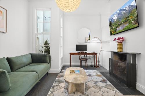 a living room with a green couch and a table at Charming 2-Bed Home with Outdoor Space in Cremorne in Melbourne