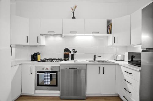 a white kitchen with a stove and a sink at Charming 2-Bed Home with Outdoor Space in Cremorne in Melbourne