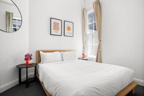 a bedroom with a large white bed and a mirror at Charming 2-Bed Home with Outdoor Space in Cremorne in Melbourne