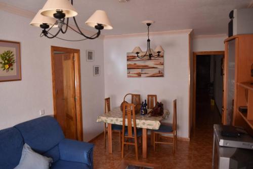sala de estar con mesa y sofá azul en Apartamento Merlin, en Roquetas de Mar