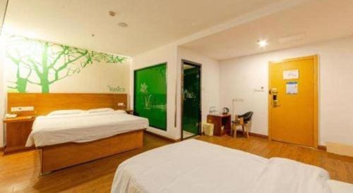 1 Schlafzimmer mit 2 Betten, einem Schreibtisch und einer grünen Wand in der Unterkunft Vatica JiangSu WuXi Xihu Middle Road Jinhai Park Hotel in Wuxi