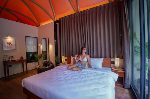 Hipnoetic Goa - Luxury Private Pool Cottages في Quepem: امرأة جالسة على سرير في غرفة فندق