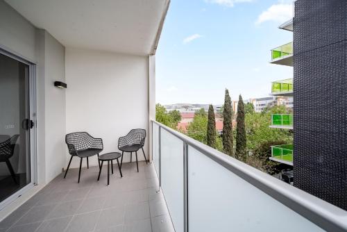 a balcony with three chairs and a table on it at Lakeside 1-Bed with AC, Parking & Balcony in Tuggeranong