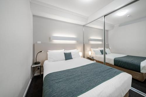 a hotel room with two beds and a mirror at Lakeside 1-Bed with AC, Parking & Balcony in Tuggeranong
