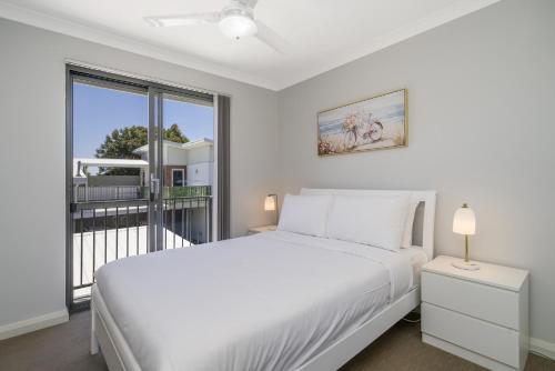 a white bedroom with a large bed and a window at Sunny 2-Bed in Quiet Location with Balcony in Perth