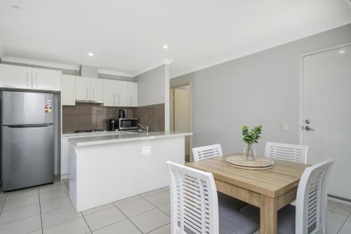a kitchen with a wooden table and white cabinets at Sunny 2-Bed in Quiet Location with Balcony in Perth