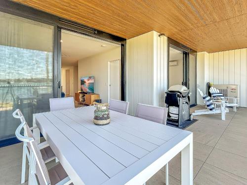 Una mesa y sillas blancas en una habitación. en 3-Bed: Riverfront Alfresco Dining & Rooftop Pool, en Batemans Bay