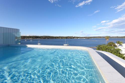 a large swimming pool with a view of the water at 3-Bed: Riverfront Alfresco Dining & Rooftop Pool in Batemans Bay