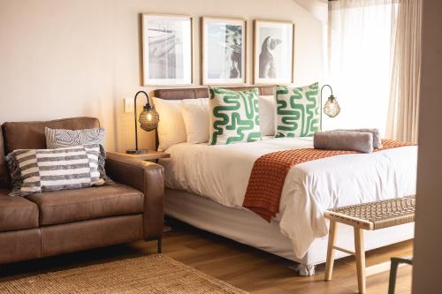赫曼努斯Oceanfront Studios - Hermanus Waterfront Apartments的带床和椅子的卧室