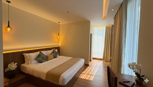 um quarto de hotel com uma cama e uma janela em The Miste Munnar By D2V em Munnar