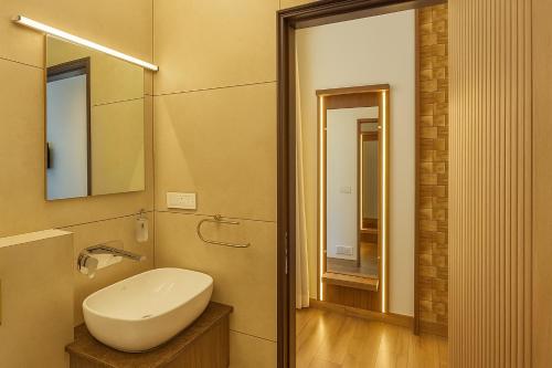 um banheiro com pia branca e espelho em The Miste Munnar By D2V em Munnar