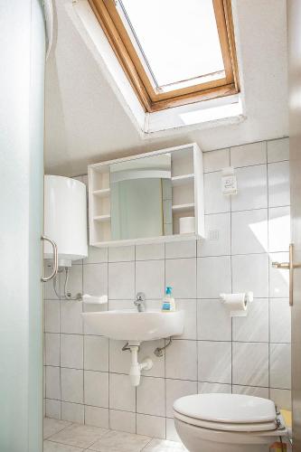 a bathroom with a sink and a toilet and a skylight at Ante Apartments in Trstenik