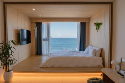 a bedroom with a bed and a large window with the ocean at Hygge Hotel in Seogwipo