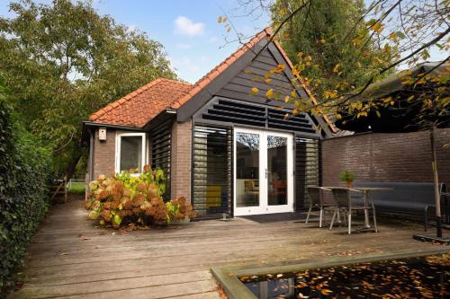 a house with a wooden deck with a table at B&B Bij ons achterom Loon op Zand in Loon op Zand