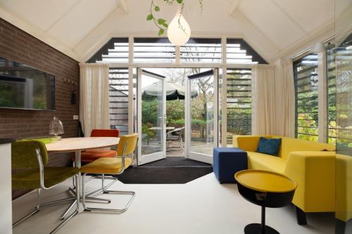 a living room with a yellow couch and chairs at B&B Achterom in Loon op Zand