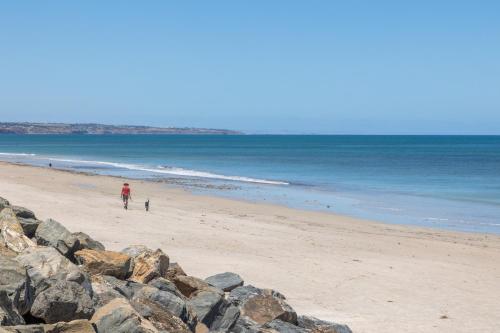 a person and a dog walking on a beach at Elegant 3-Bed Home Steps from Sunny Glenelg Beach in Glenelg