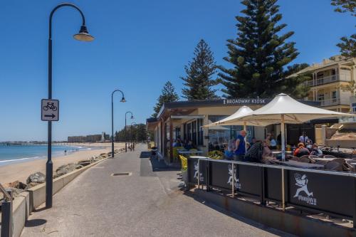 a restaurant with an umbrella on the beach at Elegant 3-Bed Home Steps from Sunny Glenelg Beach in Glenelg