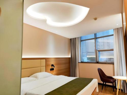 a hotel room with a bed and a window at GreenTree Inn Heze Railway Station Hotel in Zhaolou