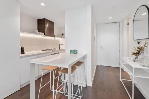 a white kitchen with a counter and stools at Chic 2-Bed with Free Parking in South Yarra in Melbourne