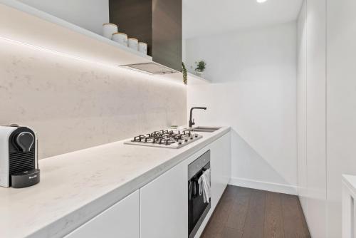 a white kitchen with a stove and a sink at Chic 2-Bed with Free Parking in South Yarra in Melbourne