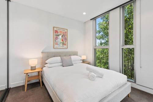 a bedroom with a white bed and two windows at Chic 2-Bed with Free Parking in South Yarra in Melbourne