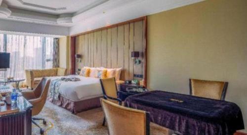 ein Hotelzimmer mit einem Bett und einem Tisch und Stühlen in der Unterkunft Wyndham Grand Plaza Royale Xianglin Shaoyang in Shaoyang