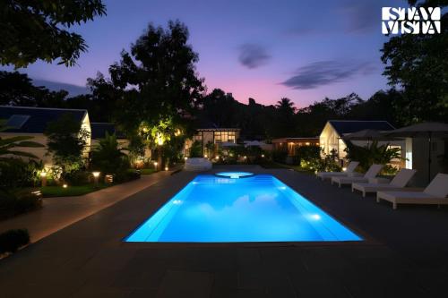 une piscine dans un jardin la nuit dans l'établissement StayVista at Luma - 350 mtr from Mandwa Jetty, à Alibaug