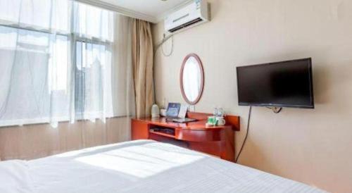 a bedroom with a bed and a flat screen tv at GreenTree Inn Langfang GuanGYAng District GuanGYAng Road City Government Express Hotel in Nanjianta