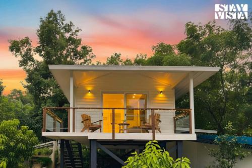 une minuscule maison avec une terrasse qui l'entoure au coucher du soleil dans l'établissement StayVista at Luma - 350 mtr from Mandwa Jetty, à Alibaug