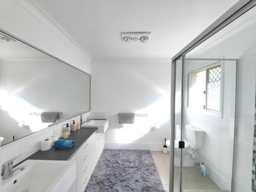 ein Badezimmer mit Waschbecken und Glasdusche in der Unterkunft Stylish Cosy Retreat in North Lakes all Air-Con in North Lakes