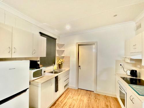 una cocina blanca con armarios blancos y una puerta en Standard Whitmore Guesthouse, en Adelaida