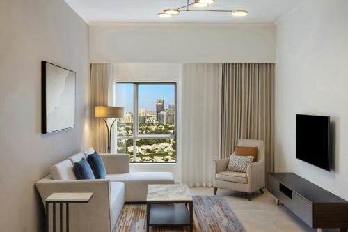 a living room with a couch and a chair and a television at Vintage Grand Hotel Apartments Dubai in Dubai