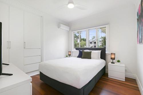 a white bedroom with a large bed and a window at Spacious 3-Bed Home in Morningside with Backyard in Brisbane