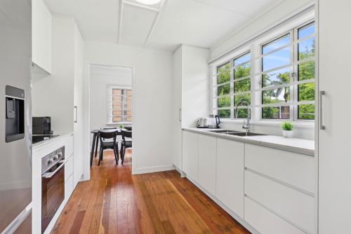 a kitchen with white cabinets and a dining room with a table at Spacious 3-Bed Home in Morningside with Backyard in Brisbane