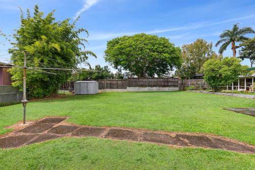 a large yard with a fence and trees at Spacious 3-Bed Home in Morningside with Backyard in Brisbane