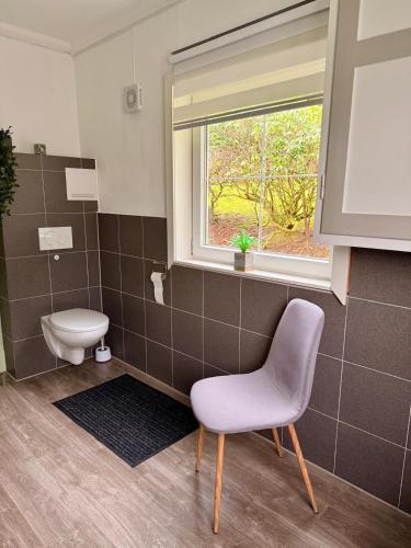 a bathroom with a toilet and a chair and a window at Haus Harald in Tysnes