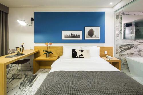 a bedroom with a bed and a desk and a tub at Hotel Denim Seoul in Seoul