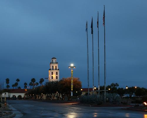 a building with a clock tower at night with flags at Hotel Mission De Oro in Santa Nella Village