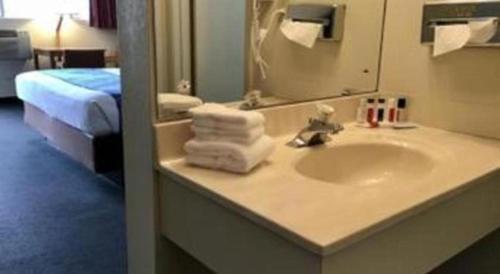 a bathroom with a sink with a mirror and a bed at Travelodge by Wyndham Powell in Powell