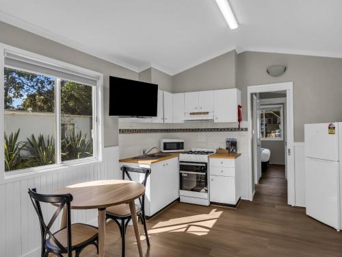 a kitchen with white appliances and a table and chairs at Kalaru Holiday Village in Tathra