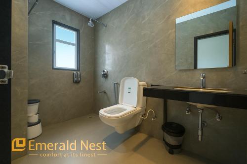 une salle de bain avec toilettes, lavabo et miroir dans l'établissement Emerald Nest, à Pandharpur