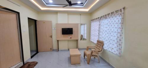 a room with a chair and a table and a tv at Sri Srinivasa Lodge in Mārkāpur