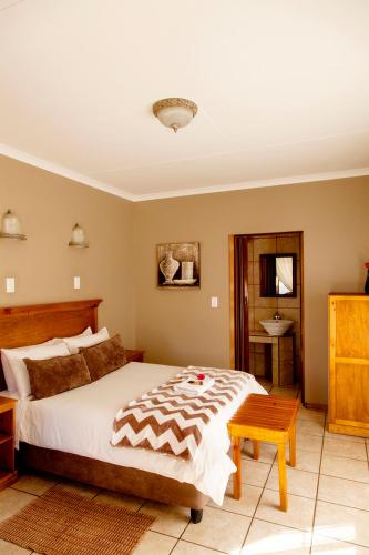 a bedroom with a large bed and a sink at Welgerust Bed & Breakfast in Piet Retief
