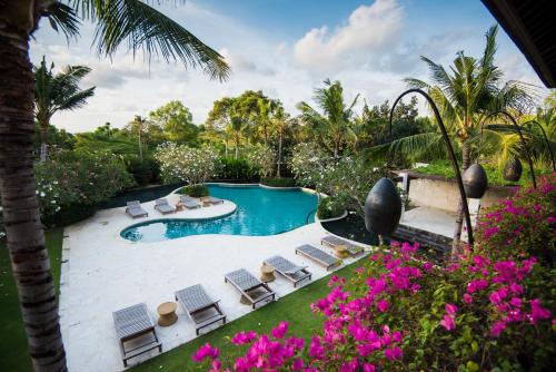 an image of a pool with chairs and flowers at Luxury Apartment at AYANA Residences in Jimbaran